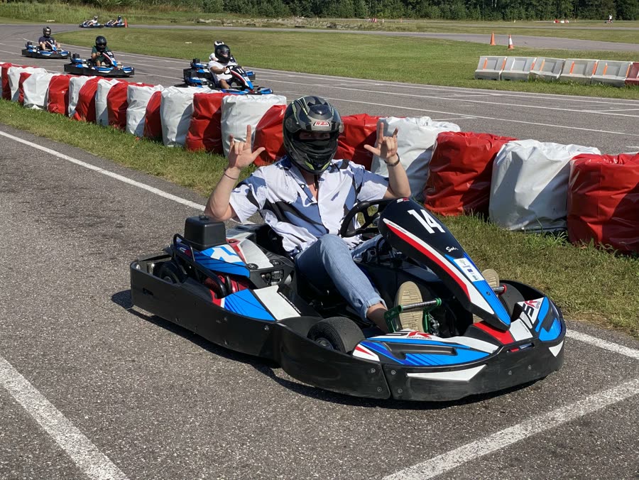 Two of the team in racing overalls at a karting track